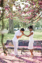 Fototapeta premium Side view of the young couple in love who standing in the park and man kissing woman's hand