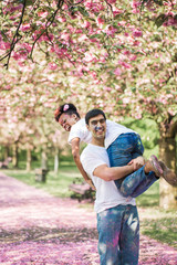 The young happy man holding the young smiling woman on a shoulder in the park with paints on their faces