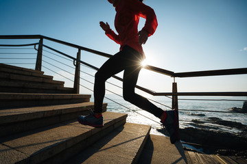 sporty fitness female runner running upstairs on coast trail