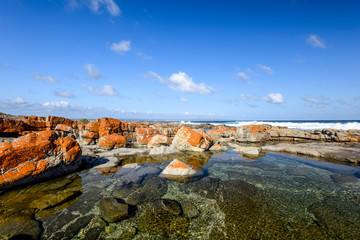 Fototapeta na wymiar Beautiful view of rock pools at the Bosbokduin Nature Reserve in Still Bay, Western Cape Province, South Africa. Ocean waves breaking in the background.