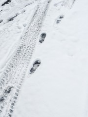 fußspuren und reifenspuren im weißen schnee im winter