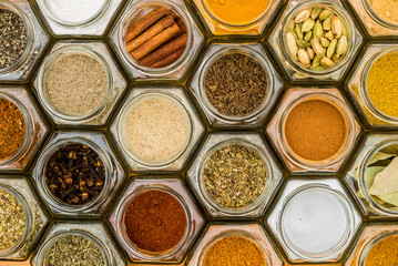 Spices and herbs in hexagon glass jars. Top view.