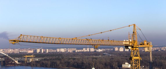 yellow industrial construction crane against blue sky