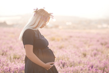 Pregnant woman posing in meadow. Motherhood. 