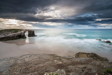 storm on the beach of the Cathedrals, with threatening clouds on the horizon unloading rain