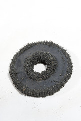 Circular magnet with iron particles on white background.