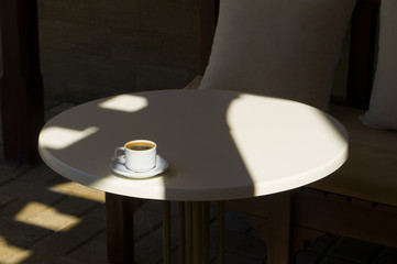 Hot coffee on white table with beautiful light and shadow. Morning cup of coffee.