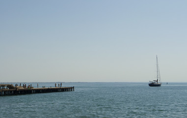 Hot midday on the Black Sea. Three sailing boats on the surface of calm sea.
