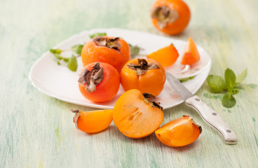 Fresh ripe persimmons in a dish on the kitchen table