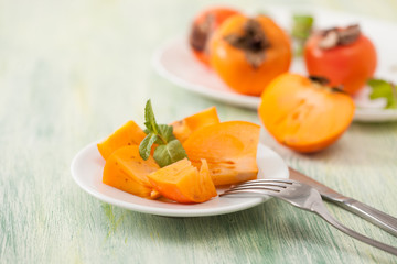 The sliced persimmon on a plate on the table
