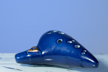 A blue ocarina in front of blue background