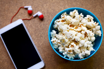 Smartphone and popcorn in bowl