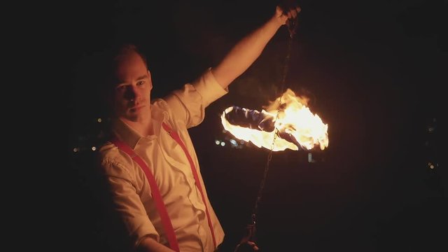 Male artist performing fire show at dark in slow motion.