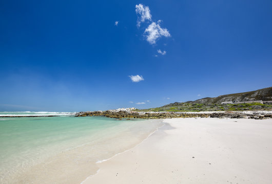 Beach view with white sand, rocks and crystal clear water at Brandfontein - Rietfontein Nature Reserve near Cape Agulhas, Western Cape Province, South Africa.
