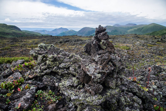 Pyramyd of lava stones and large volcano valley surrounded with mountains at background. Scenic landscape, Russia, Siberia.