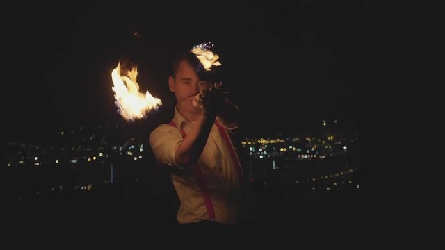 Male artist performing fire show at dark in slow motion.