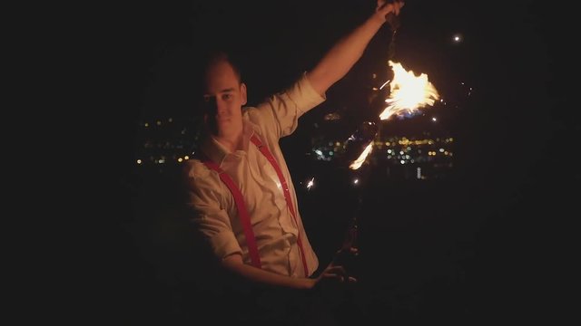 Male artist performing fire show at dark in slow motion.