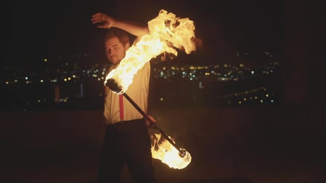 Male artist performing fire show at dark in slow motion.