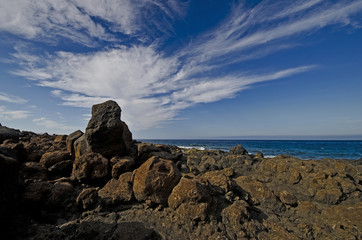 Steinige Meeresküste mit spektakulärem Wolkenhimmel.
