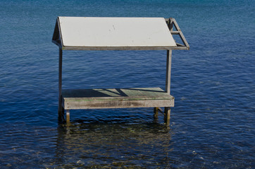 Überdachter Holztisch der im Wasser steht.
