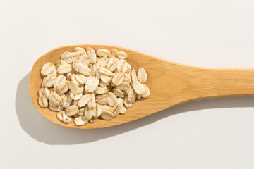 Oat cereal grain. Nutritious grains on a wooden spoon on white background.