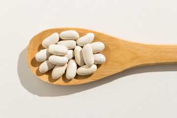 Fototapeta na wymiar Navy Bean legume. Nutritious grains on a wooden spoon on white background.