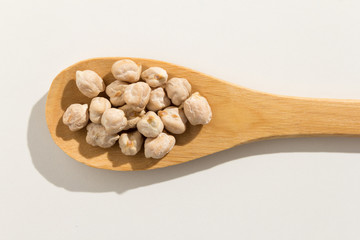 Chickpeas legume. Nutritious grains on a wooden spoon on white background.