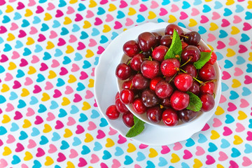 Cherries in a white plate on the table.