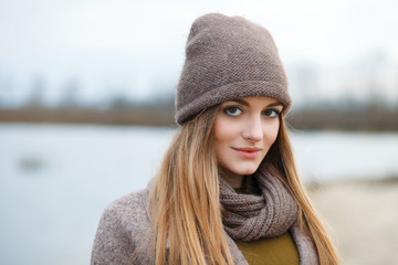 Stylish blonde woman in trendy urban outwear posing cold weather on the river bank. Vintage filter film saturated color. Fall mood concept.