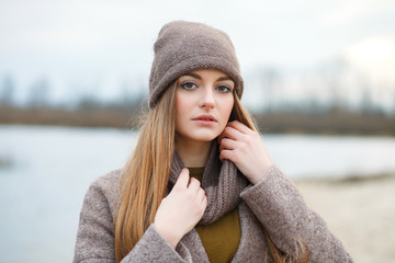 Stylish blonde woman in trendy urban outwear posing cold weather on the river bank. Vintage filter film saturated color. Fall mood concept.