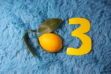 The third month of pregnancy. Fetus is a child the size of a lemon. Lemon on a blue background. The figure is three yellow.