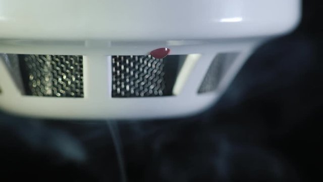 Close-up shot: The smoke detector is triggered by a trickle of dum, the red indicator lights up