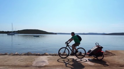 Dad driving his baby on a weekend excursion with bike on a summer day by the sea
