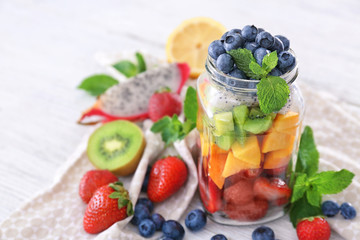 Mason jar with fruits and berries on table