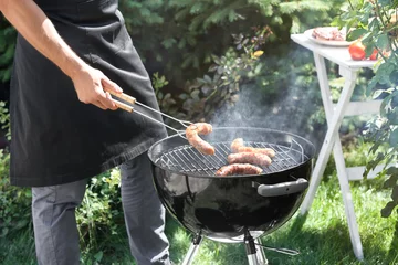 Crédence de cuisine en verre imprimé Pique-nique Man preparing delicious sausages on barbecue grill outdoors