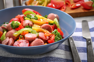 Vegetable salad with sausage in bowl on kitchen table