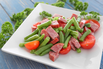 Plate with vegetable salad and sausage on table, closeup