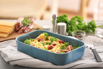 Pasta with sausage and cheese in ceramic baking dish on fabric