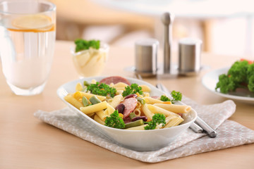 Pasta with sausage and vegetables in ceramic bowl on table