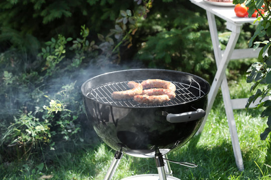 Barbecue grill with tasty sausages on backyard