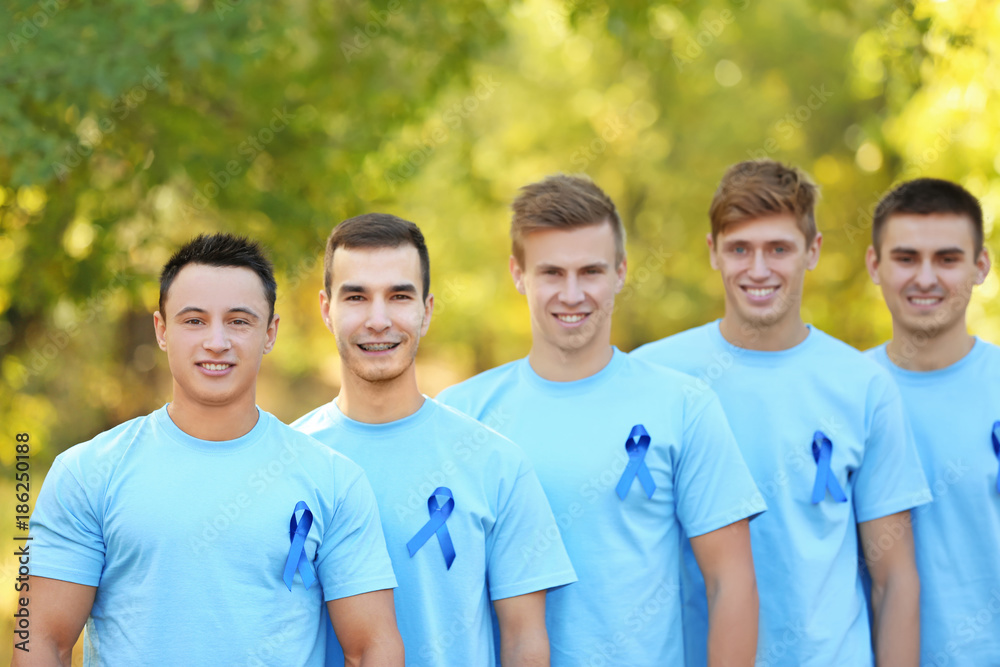 Poster Young men in t-shirts with blue ribbons outdoors. Prostate cancer awareness concept