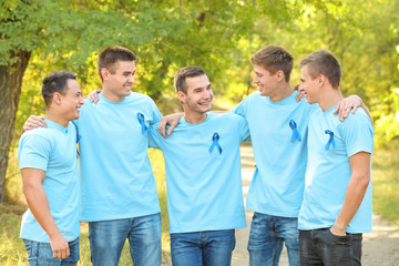 Young men in t-shirts with blue ribbons outdoors. Prostate cancer awareness concept