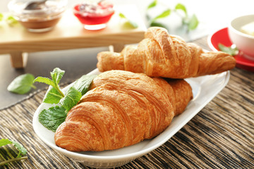 Plate with tasty croissants on table, closeup