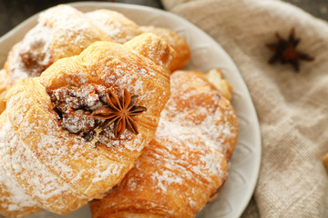 Plate with tasty croissants on table, closeup