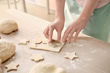Woman preparing puff pastry at table in kitchen