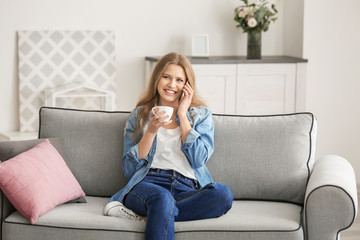 Obraz premium Beautiful woman speaking by cellphone while resting on sofa at home