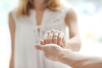 Man holding fiancee's hand with engagement ring on blurred background