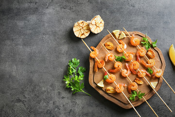 Delicious fried shrimps with garlic on wooden board, top view