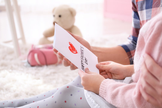 Little girl giving her dad greeting card for Father's Day