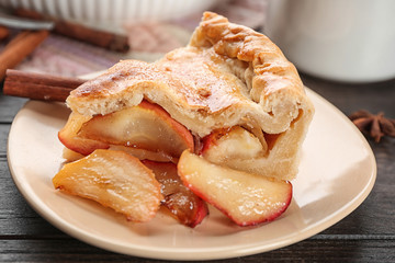 Plate with slice of freshly baked apple pie on table